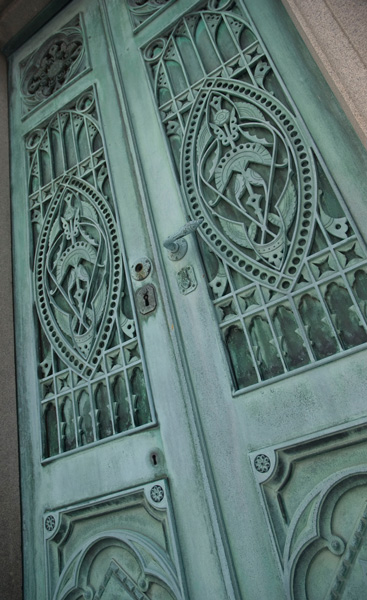 Two heavily ornamented, metal doors have turned a blue-green with time.