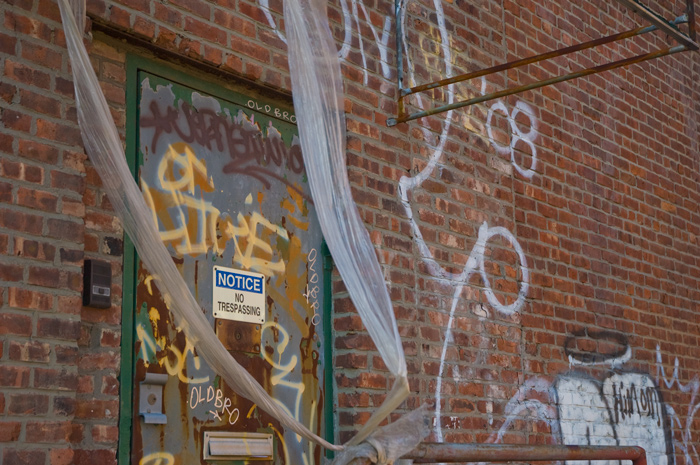 A sign on a door in a heavily graffiti covered building warns against trespassing.