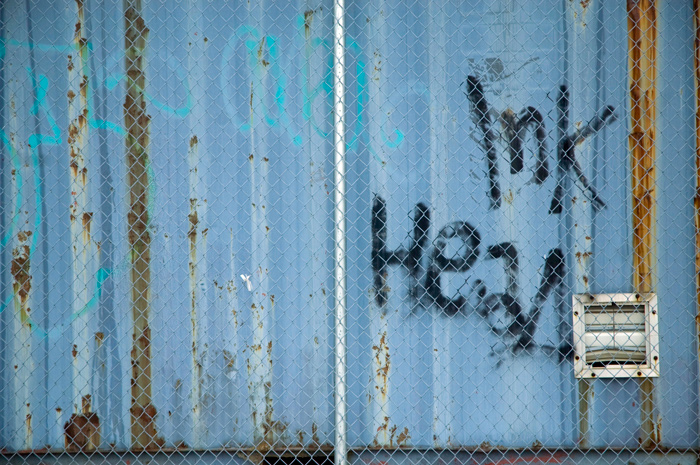 The graffiti tag 'Inkhead' has been sprayed on a blue corrugated metal sheet.