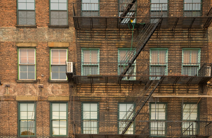 The faded word 'England' appears on a brick wall, between rows of windows and fire escapes.