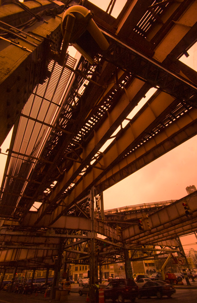 The tracks of an elevated train dominate the picture, with converging traffic below.