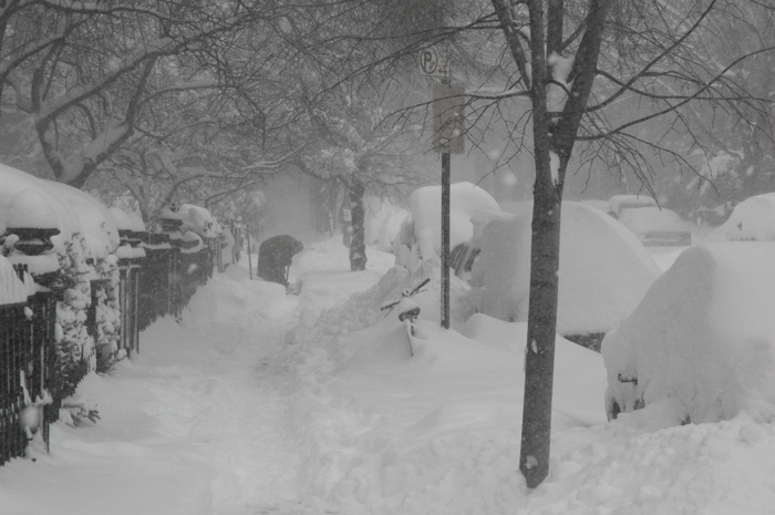 A person chops at built up snow, to shovel.