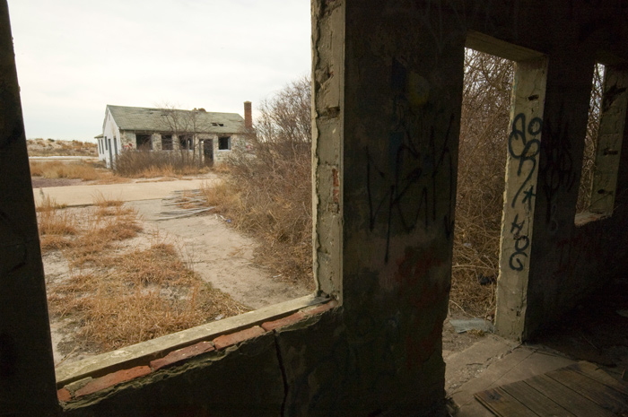 An abandoned military building is seen throught the window of another like it.