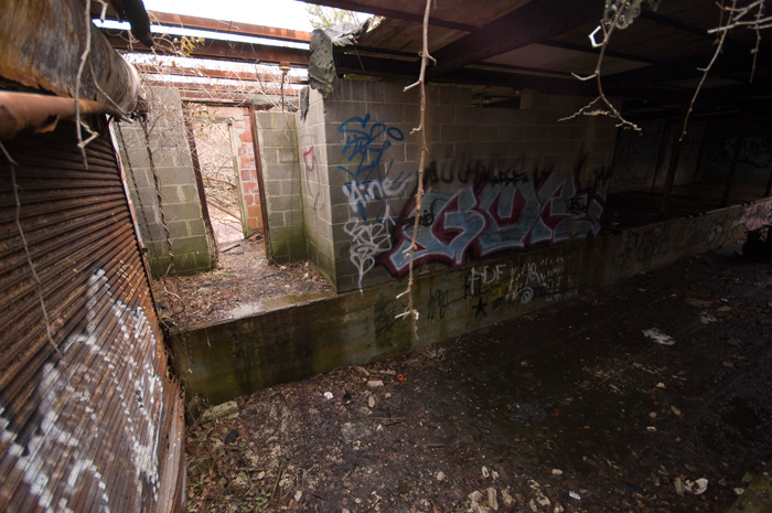 Light leads through an unadorned cinder block doorway, into a dark area.