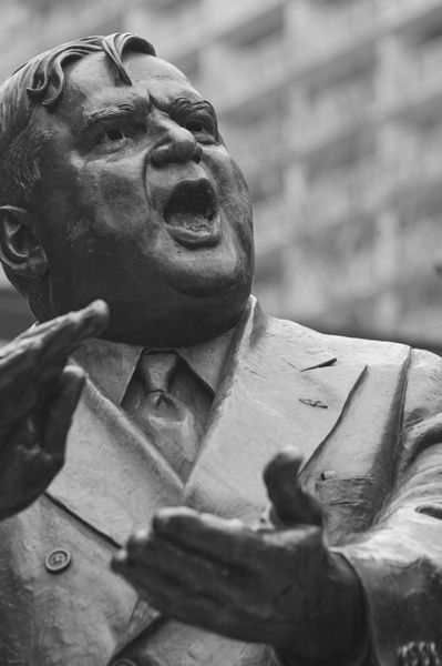 A statue of Fiorello La Guardia shows him clapping his hands.