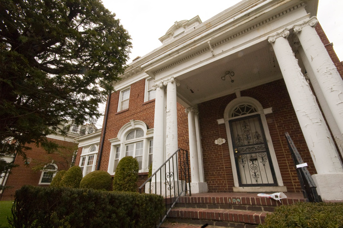 Photo of a brick home with white pillars at its entrance.