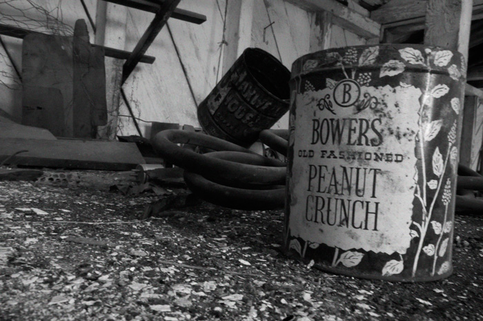 An old can of 'peanut crunch' sits on a table in an abandoned barn.