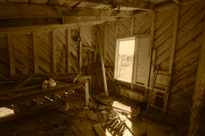 Sunlight streams through a window of an abandoned barn, highlighting a bushel.