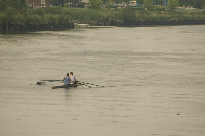 Two people in a small row boat are alone in a river.