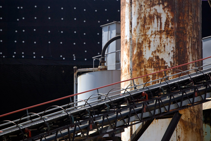 A rusty chute from a cement factory stands out against the tar paper of a subway station.