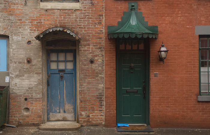 Two adjacent doors and buildings are in different states, one well kept, the other far more aged.