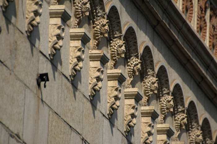 Rows of stone faces line the top of a building.