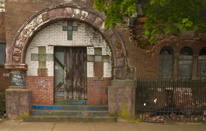 Scattered planks have been nailed over the entrance to a 19th century brick building.