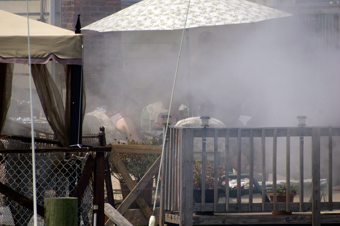 A dinner party does its best to ignore the smoke from the grill which has overwhelmed their backyard deck.