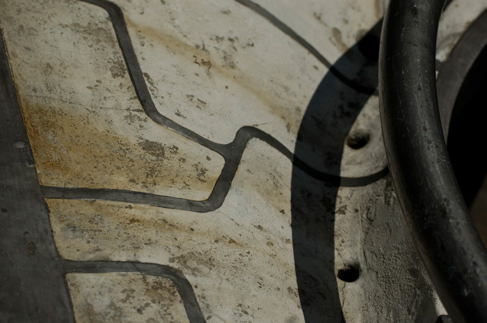 A curved, concrete bench is marked with abstract lines and signs of age.