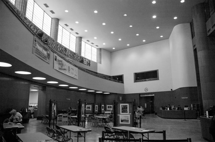 A curved room with a balcony and light coming through the windows.