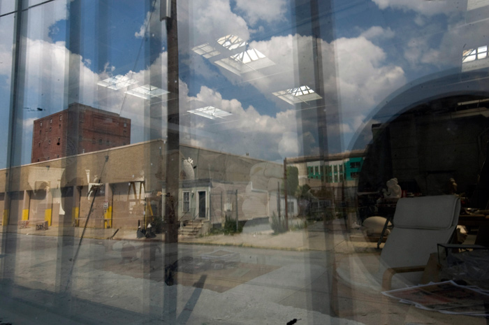 Reflected clouds from outside and skylights from inside compete for prominence on a window.