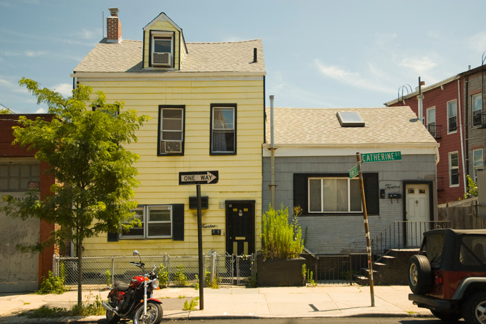 Two small wooden houses sit side by side, with a motorcycle out front.