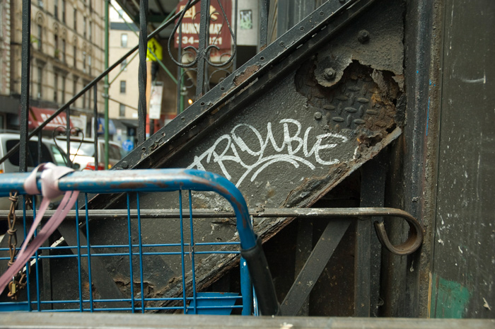 The word 'trouble' has been written on the side of an old steel staircase.