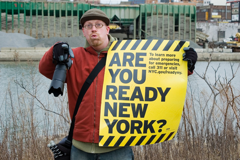 A man holds up a sign on emergency preparedness, asking New Yorkers if they are 'ready.'