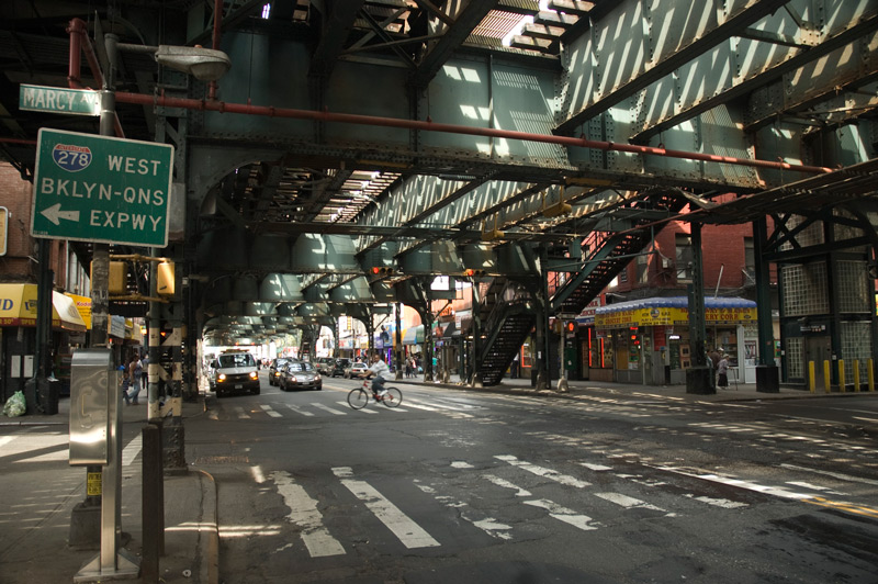 Shadows from elevated train tracks cast an intersection in darkness.