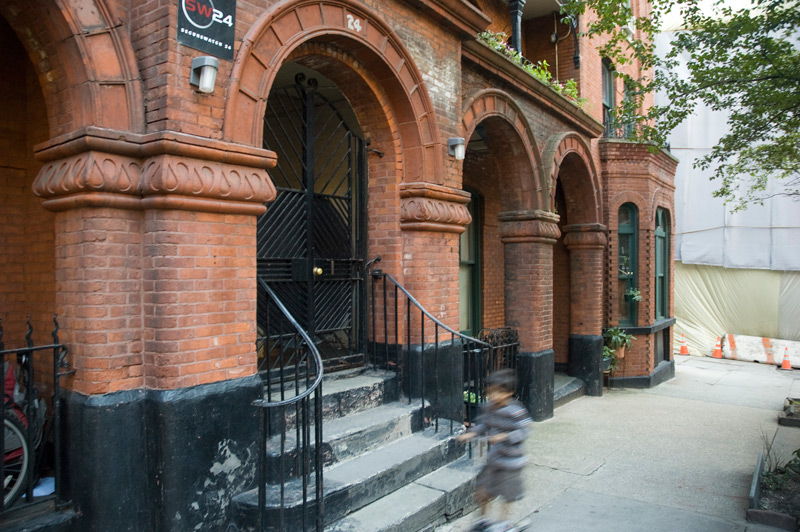 A boy, merely a blur, rides past a terra cotta building on his scooter.