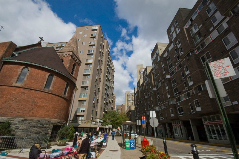 An old brick church and modern apartment towers, below a blue sky with clouds.