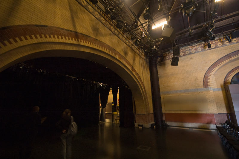 An arch of intricate brickwork extends over a deserted stage.