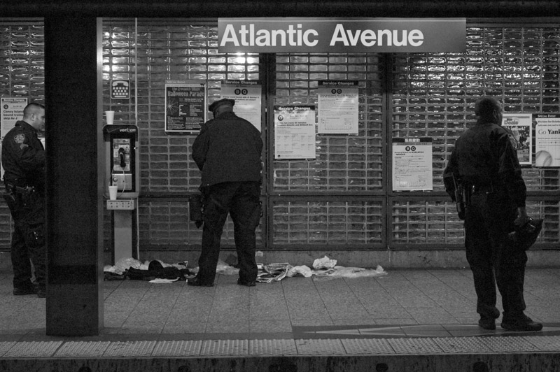 Three policemen on an empty subway platform clean up water from the rains.