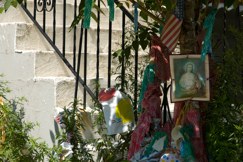 A 'Sacred Heart' print hangs on an outside stairway railing, among other miscellany.