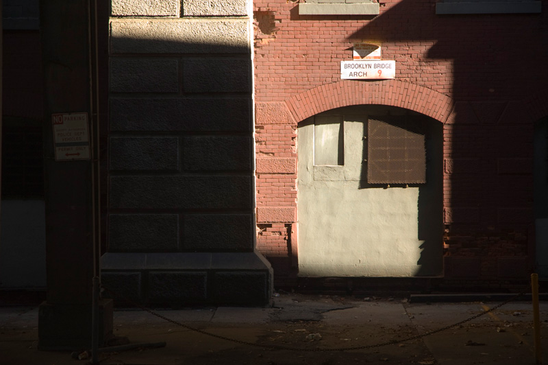 Light falls on the walled up area of a bridge's arch.