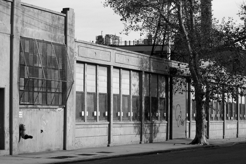 An empty street dominated by a building with protective wiring over its windows.