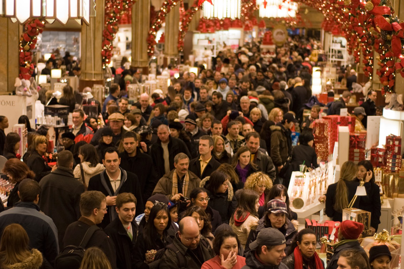 Crowds of shoppers in an aisle of a department store.