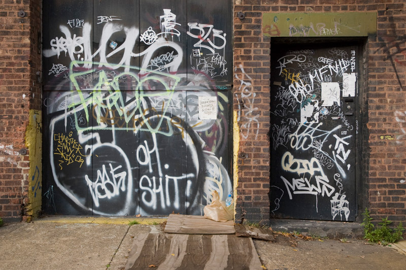 Graffiti covers a door, including the words 'Oh shit.'