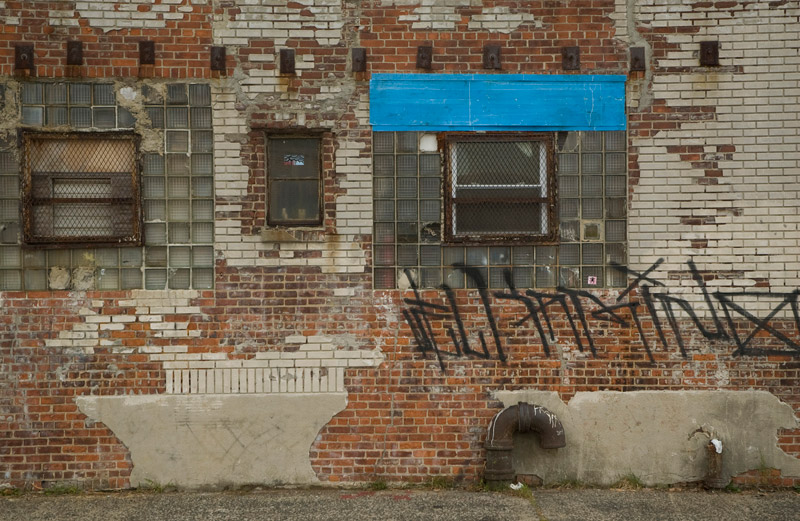 The veneer of a building in poor shape, with varieties of bricks.