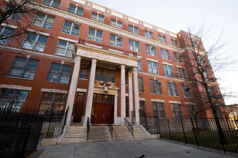 A five-story brick school building with a tall, columned entrance.