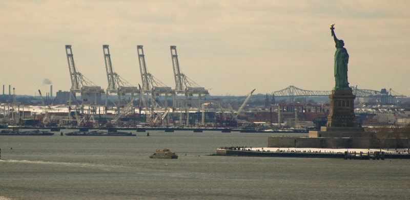 The waters approaching Manhattan, with the Statue of Liberty, loading craned, and bridges.