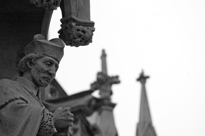 A statue of a bishop praying, with hands folded.