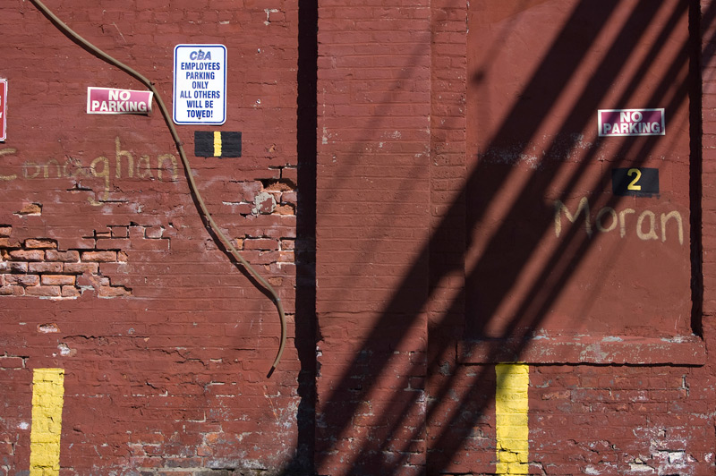 Crudely painted names on a brick wall designate parking spaces.