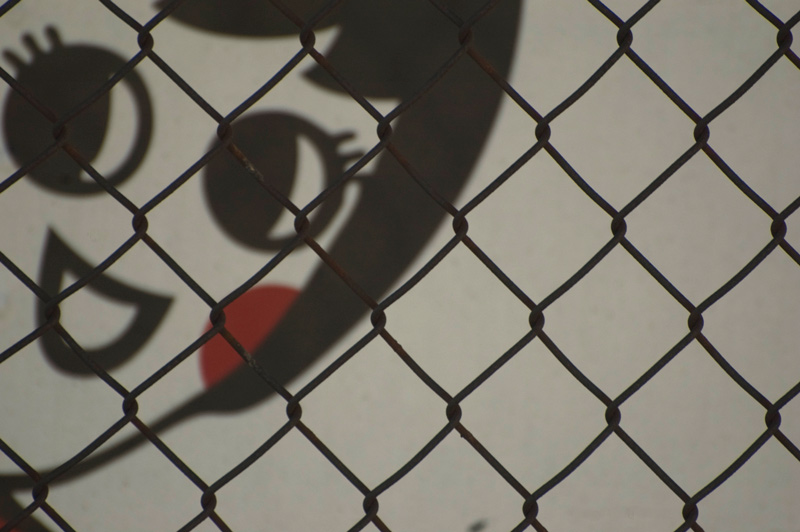 A cartoon girl on a truck, seen through a fence.