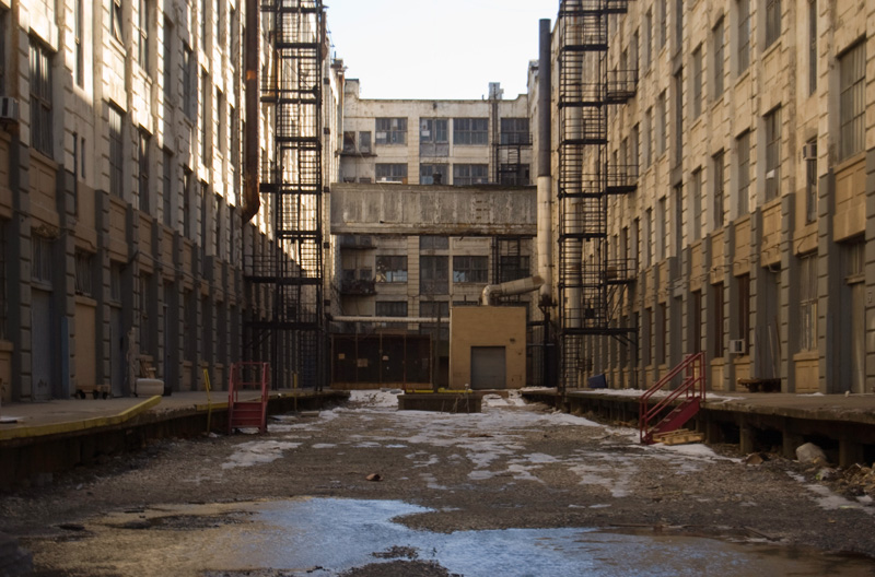 A closed alley behind tall warehouses.