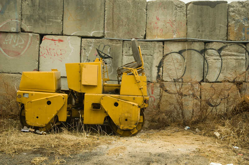 A small yellow construction vehicle, next to large concrete blocks.