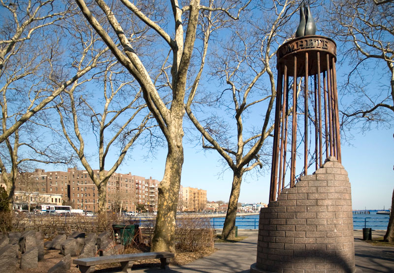 An open cylinder of bricks, bars, barbed wire, and a flame.