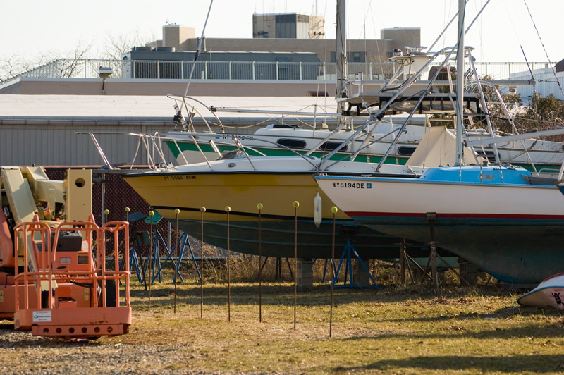 Several boats sitting in a yard in front of an institutional building.