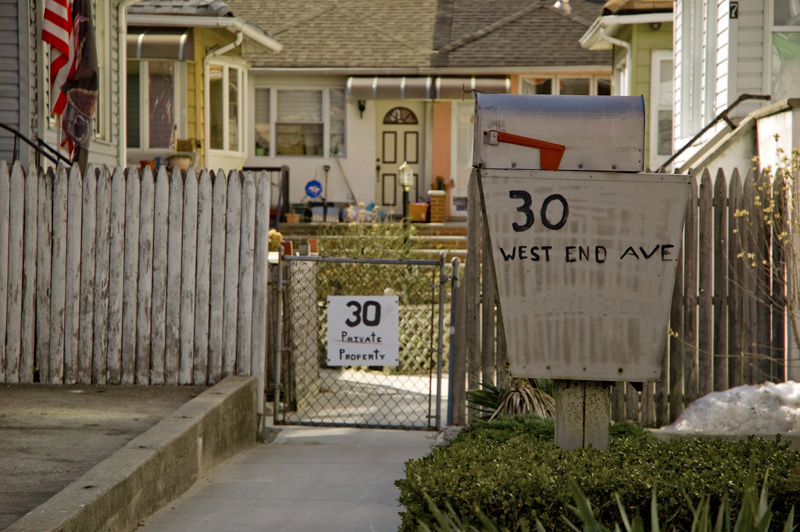 A sidewalk leads to six small homes.