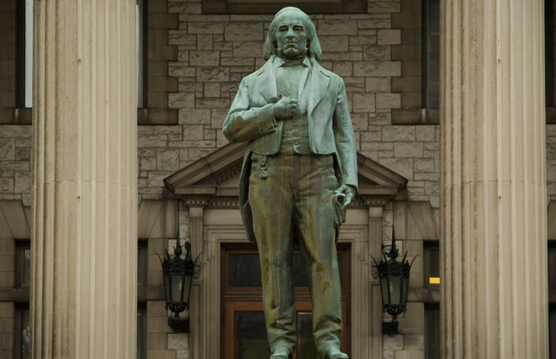 A statue of a suited man, one hand in his vest, the other at his side.