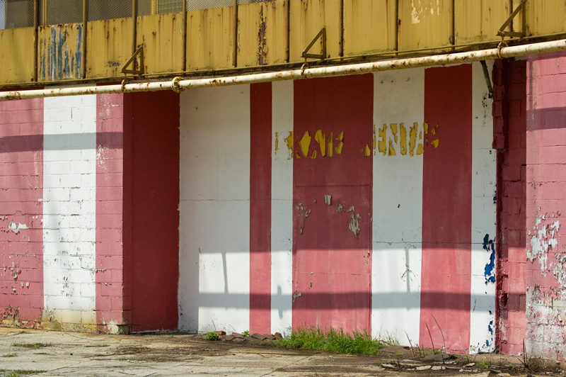 Paint is peeling on a wall with red and white stripes.