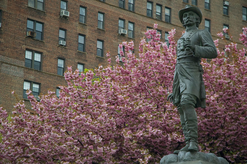 A military statue, with cherry blossoms in the background.