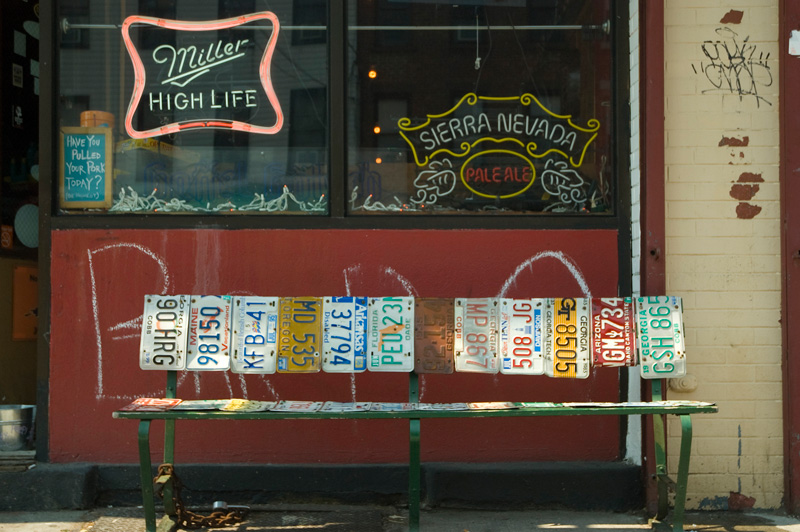 In front of a bar, a bench made of license plates.