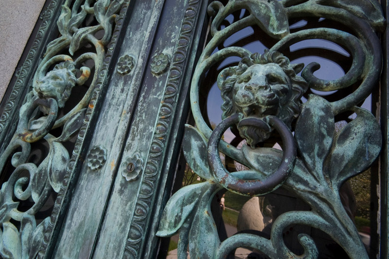 Ornate metal work of leaves and lions, on glass panes.